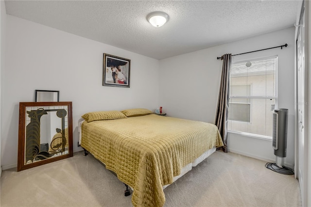 carpeted bedroom with a textured ceiling and baseboards