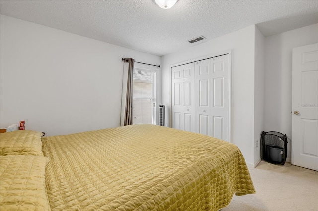 bedroom featuring light colored carpet, a closet, visible vents, and a textured ceiling