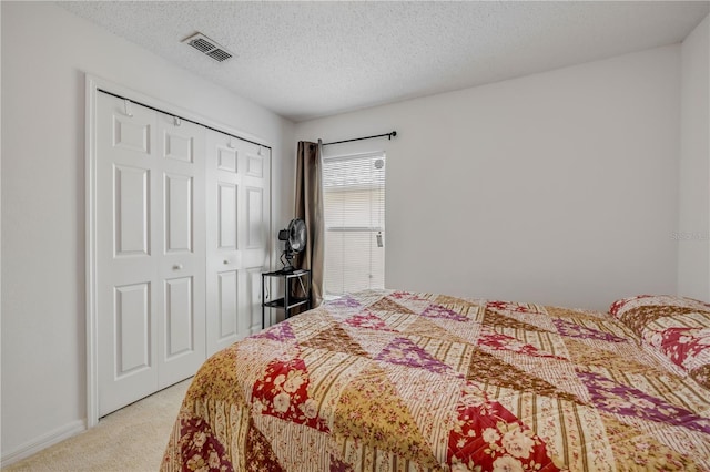 bedroom with light carpet, baseboards, visible vents, a textured ceiling, and a closet