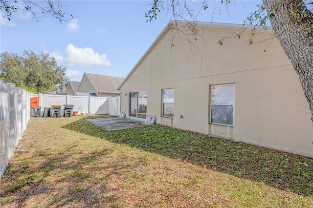 rear view of house with a patio area, a fenced backyard, a yard, and stucco siding