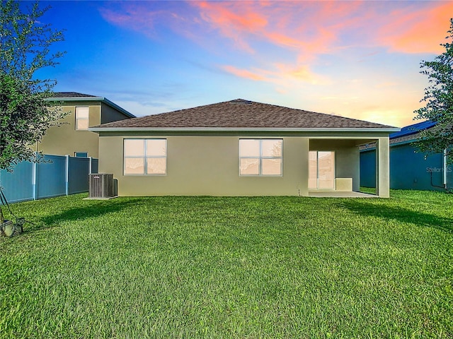 back of house with central air condition unit, a patio area, a lawn, and stucco siding