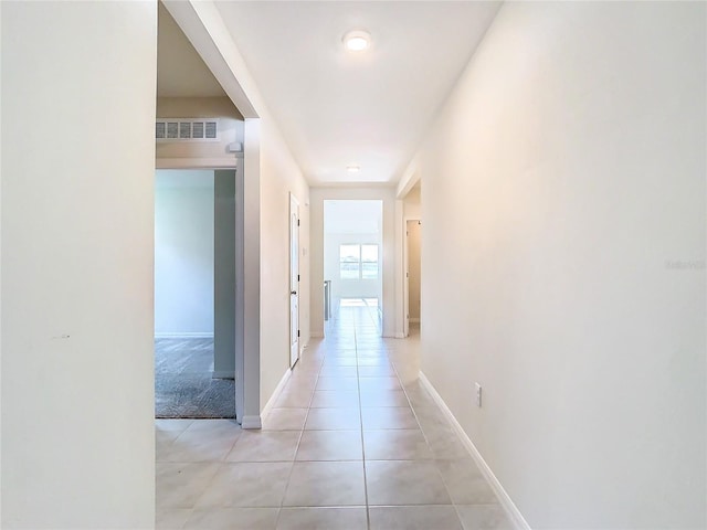 corridor featuring visible vents, baseboards, and light tile patterned floors