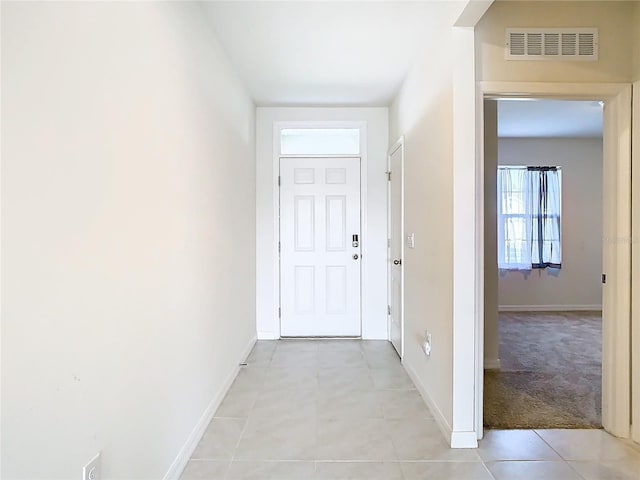 hall featuring light tile patterned floors, baseboards, and visible vents