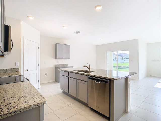 kitchen with an island with sink, light stone countertops, appliances with stainless steel finishes, and a sink