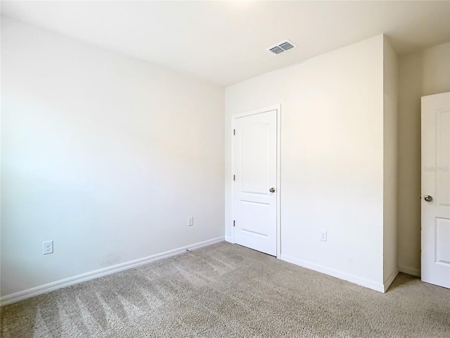 empty room with carpet, visible vents, and baseboards