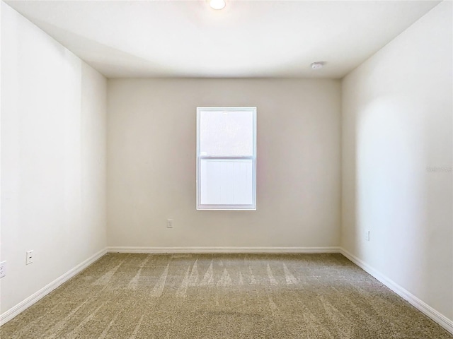 carpeted empty room featuring baseboards