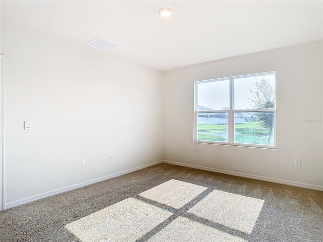 spare room with carpet, visible vents, and baseboards