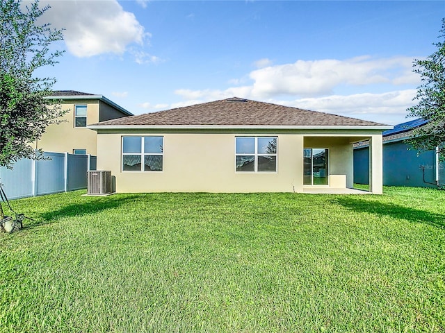 back of house featuring central AC, a yard, fence, and stucco siding