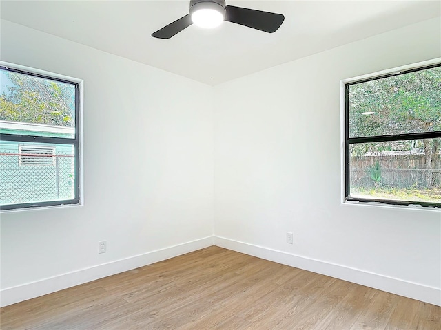 empty room with light hardwood / wood-style floors, a wealth of natural light, and ceiling fan