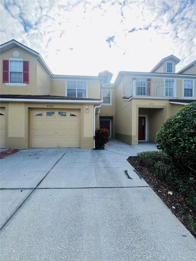 multi unit property featuring driveway, an attached garage, a balcony, and stucco siding