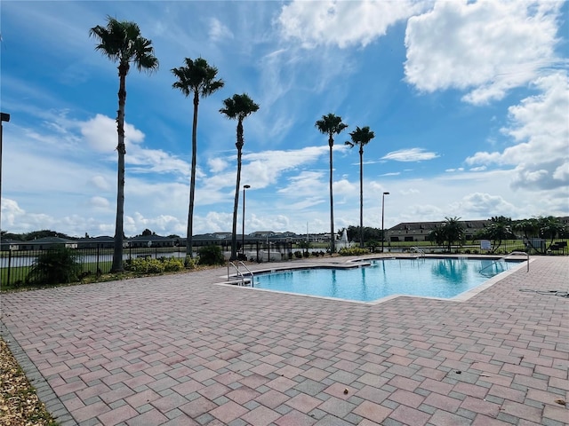 pool with a patio area and fence