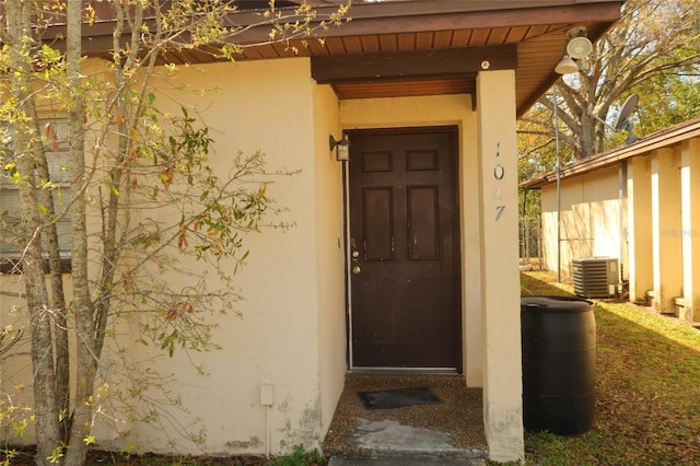 doorway to property featuring central air condition unit and stucco siding