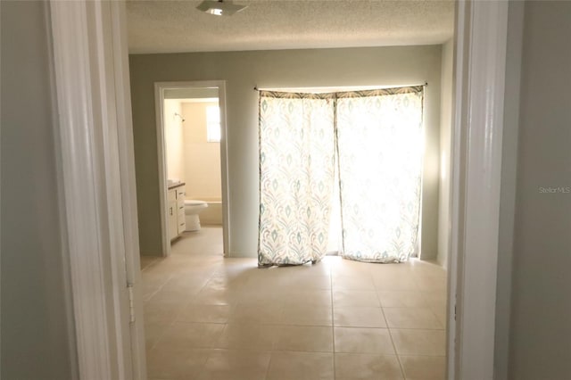 hallway with a textured ceiling and light tile patterned flooring