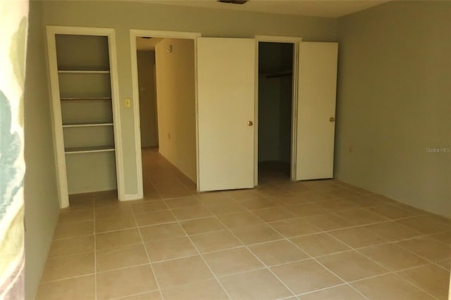 unfurnished bedroom with light tile patterned floors, a closet, and visible vents