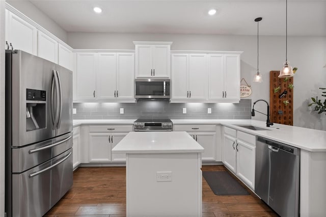 kitchen with hanging light fixtures, stainless steel appliances, white cabinets, sink, and kitchen peninsula