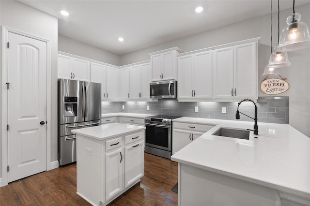 kitchen featuring stainless steel appliances, hanging light fixtures, a center island, sink, and white cabinets