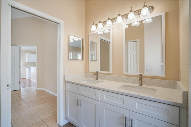 bathroom featuring double vanity, baseboards, a sink, and tile patterned floors