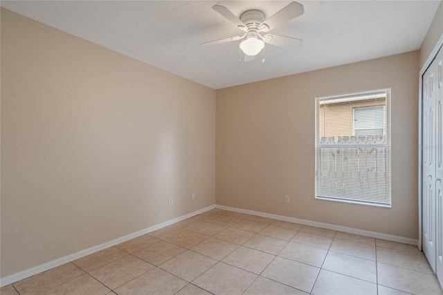 spare room featuring ceiling fan, baseboards, and light tile patterned floors