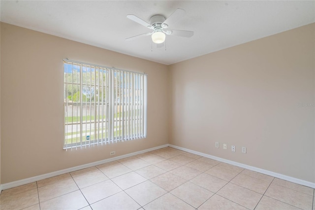 empty room featuring light tile patterned floors, ceiling fan, and baseboards