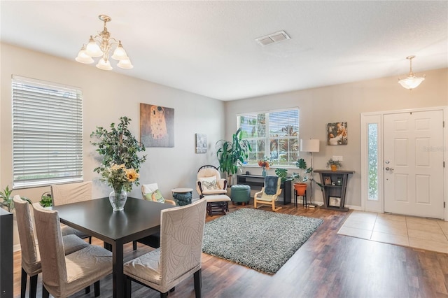 dining area with a notable chandelier, visible vents, and wood finished floors