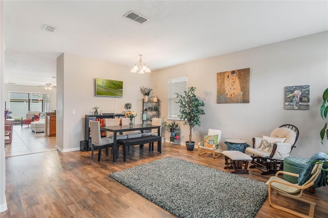 dining area featuring light wood finished floors, baseboards, visible vents, and ceiling fan with notable chandelier