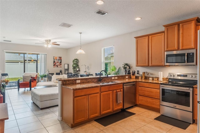 kitchen featuring visible vents, appliances with stainless steel finishes, open floor plan, a sink, and a peninsula