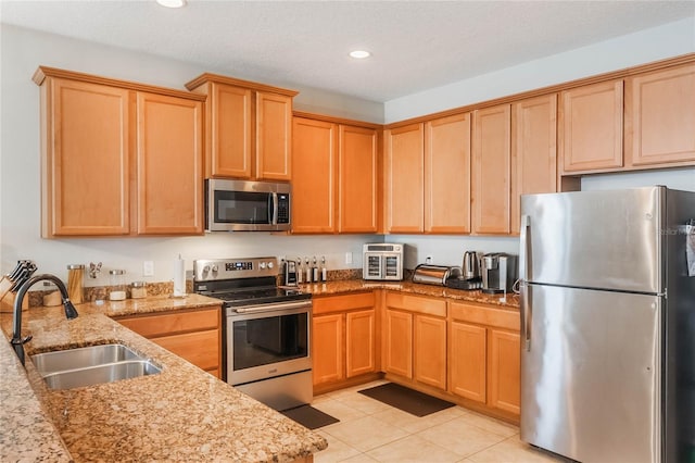 kitchen with light tile patterned floors, light stone counters, recessed lighting, stainless steel appliances, and a sink