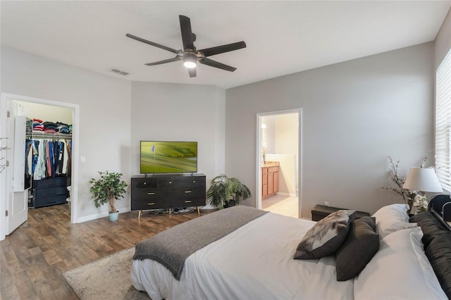 bedroom with ceiling fan, wood finished floors, ensuite bathroom, a walk in closet, and a closet