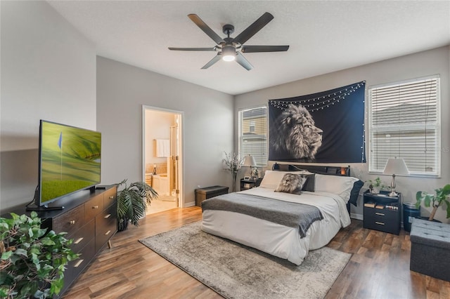 bedroom with baseboards, wood finished floors, a ceiling fan, and connected bathroom