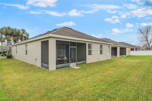 rear view of house with a sunroom, a lawn, fence, and stucco siding