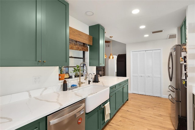 kitchen featuring light stone countertops, green cabinets, stainless steel appliances, and light hardwood / wood-style flooring