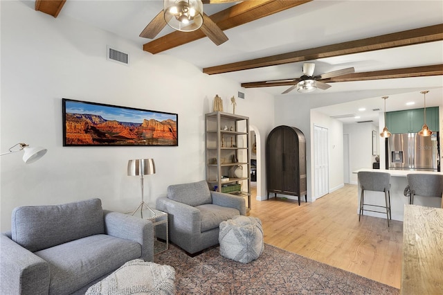 living room with vaulted ceiling with beams, ceiling fan, and light hardwood / wood-style flooring