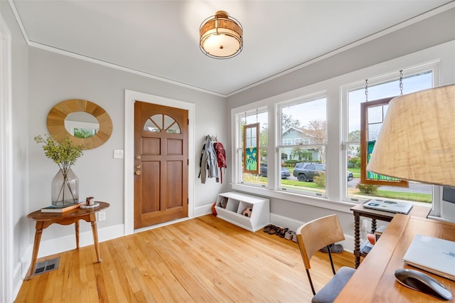 entryway featuring baseboards, light wood-style floors, visible vents, and crown molding