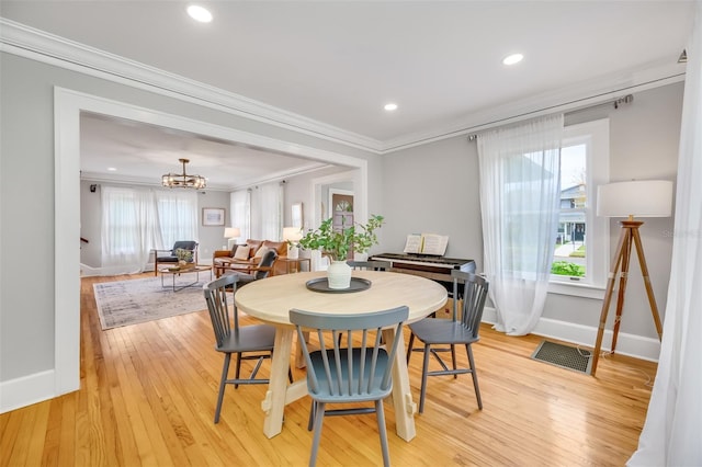 dining area with light wood finished floors, ornamental molding, visible vents, and a notable chandelier