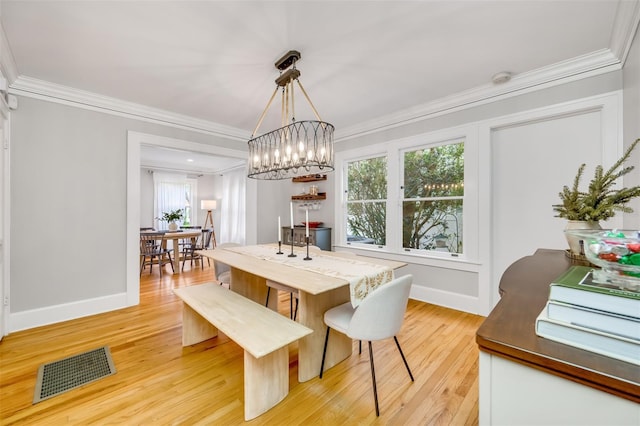 dining room featuring baseboards, light wood-type flooring, visible vents, and crown molding