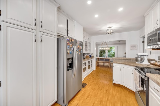 kitchen featuring light stone counters, a notable chandelier, light wood-style flooring, appliances with stainless steel finishes, and white cabinets