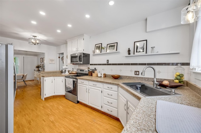 kitchen featuring hanging light fixtures, white cabinets, stainless steel appliances, and a sink