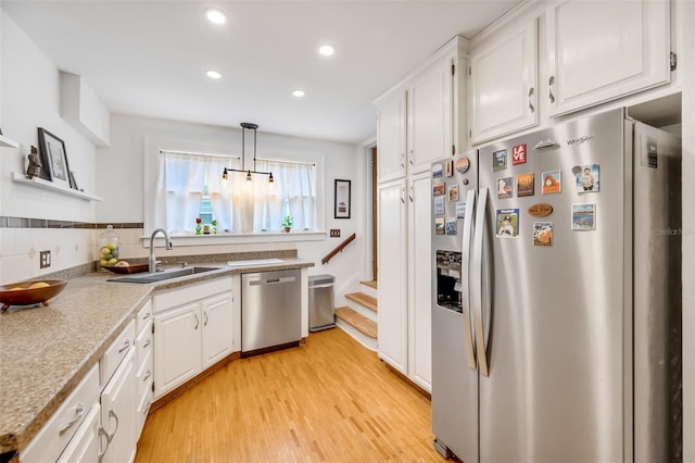 kitchen featuring a sink, white cabinets, light countertops, appliances with stainless steel finishes, and hanging light fixtures