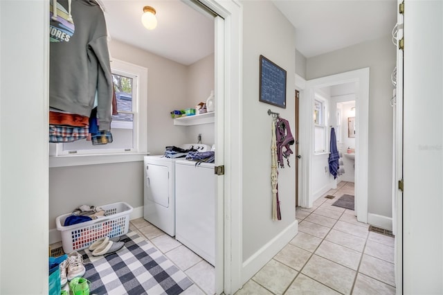 washroom with washing machine and dryer, laundry area, light tile patterned flooring, and baseboards