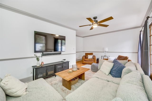 living area with ornamental molding, light wood-type flooring, baseboards, and a ceiling fan