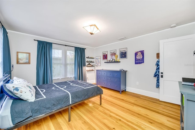 bedroom featuring baseboards, ornamental molding, visible vents, and light wood-style floors