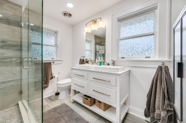 bathroom with double vanity, visible vents, toilet, a stall shower, and a sink