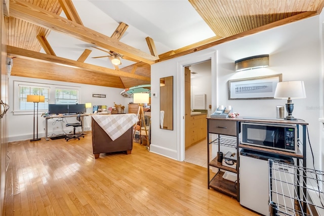 kitchen featuring lofted ceiling with beams, light wood-style floors, a kitchen island, ceiling fan, and black microwave