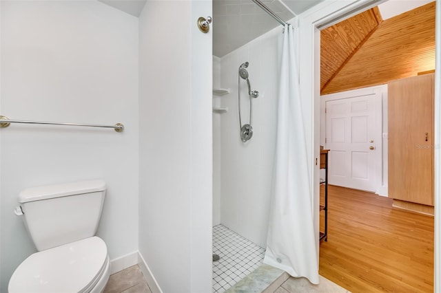 bathroom with toilet, a shower stall, baseboards, and wood finished floors