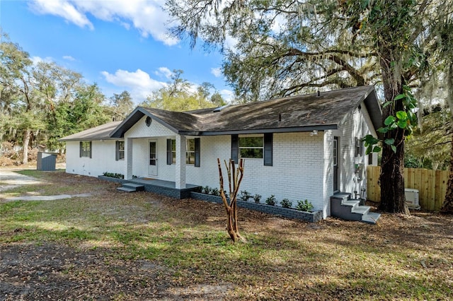 ranch-style home featuring brick siding and fence