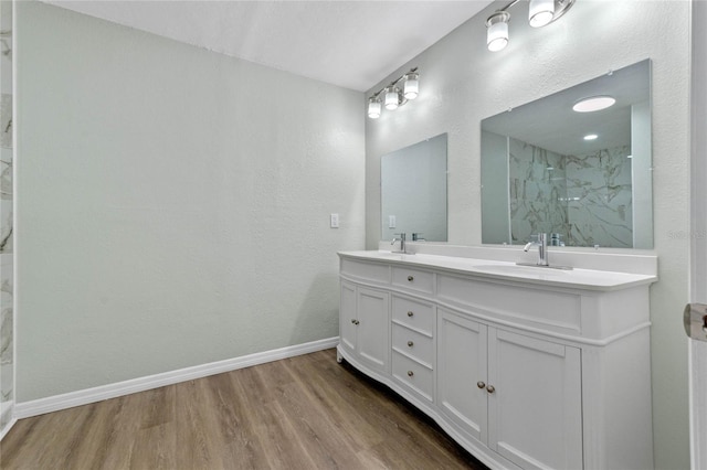 full bathroom featuring double vanity, baseboards, a sink, and wood finished floors