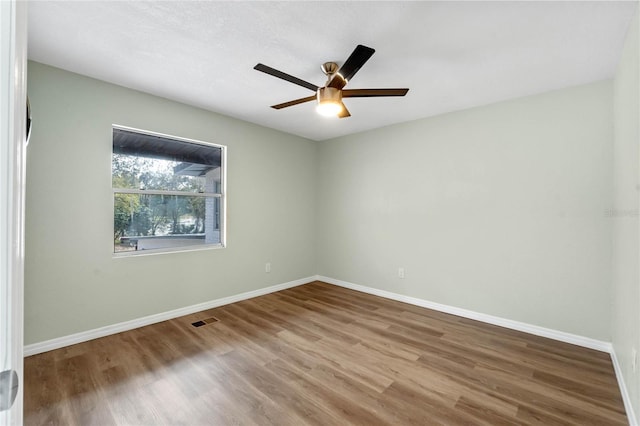 spare room featuring baseboards, visible vents, and wood finished floors