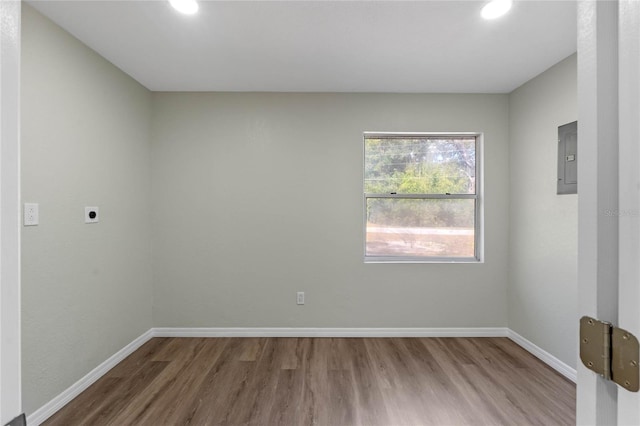 unfurnished room featuring recessed lighting, electric panel, baseboards, and wood finished floors