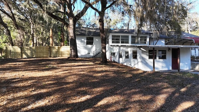 rear view of property featuring brick siding and fence