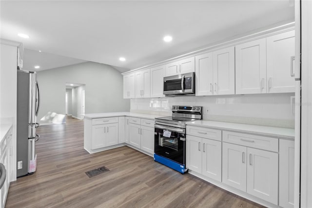 kitchen with stainless steel appliances, light countertops, white cabinetry, and wood finished floors